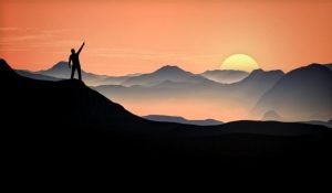 man raising arm at the top of the mountain victory and aspirat